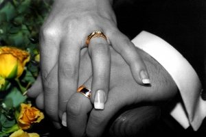 Two people holding hands with wedding bands on